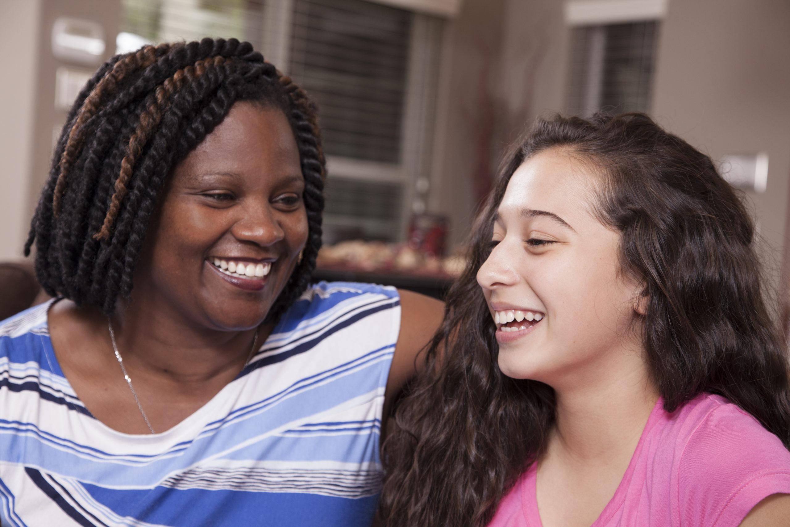 Multi-ethnic family.  Teenage girls and mom at home.  Hugs.